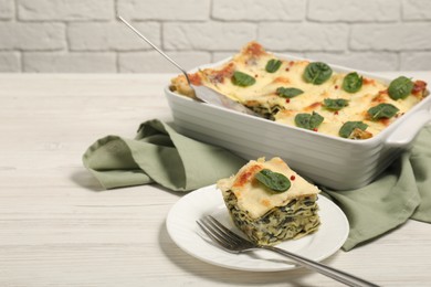 Photo of Delicious spinach lasagne served on white wooden table, space for text