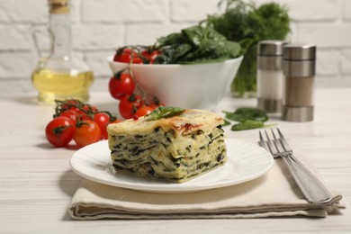 Photo of Piece of delicious spinach lasagne served on white wooden table