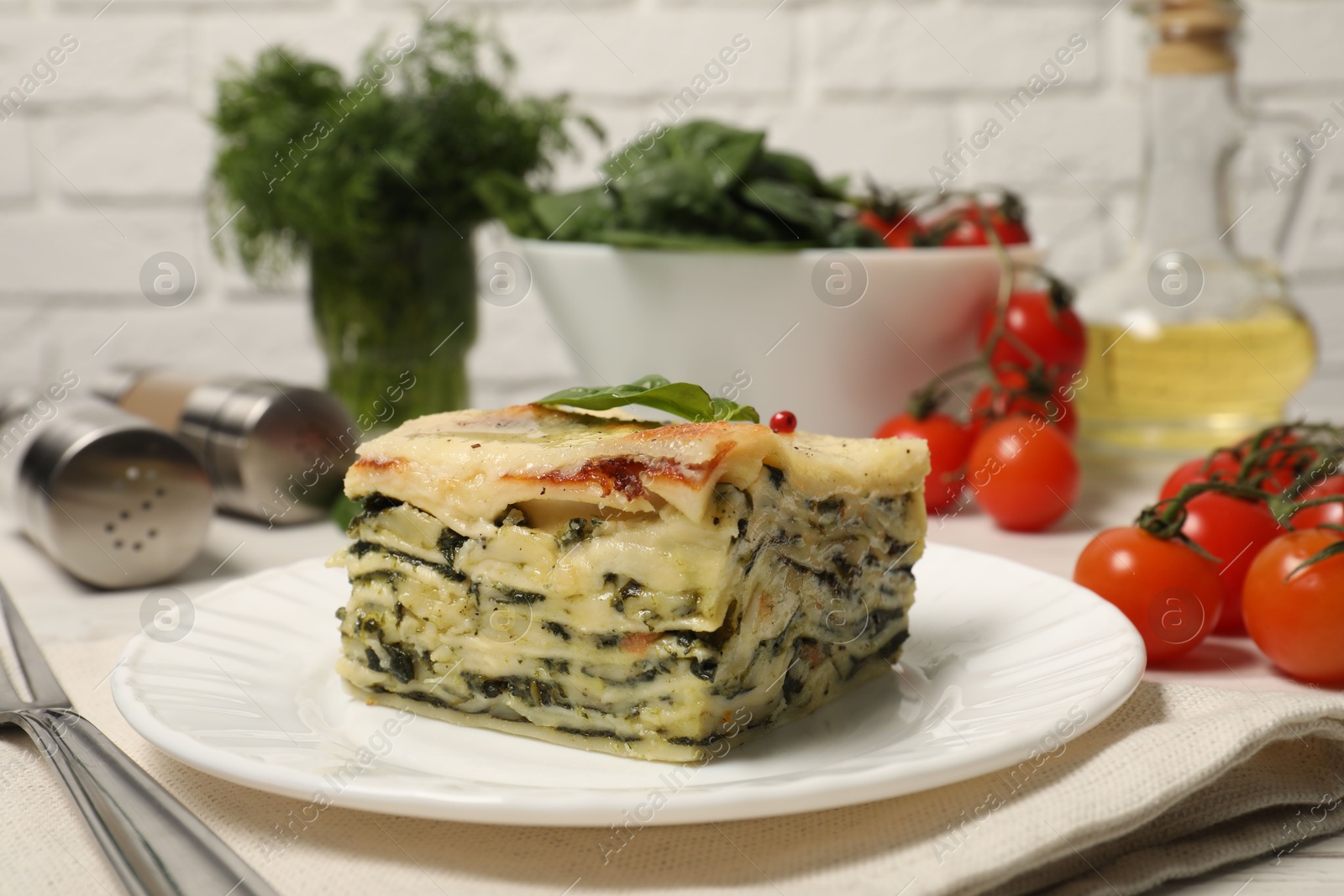 Photo of Piece of delicious spinach lasagne served on white table, closeup