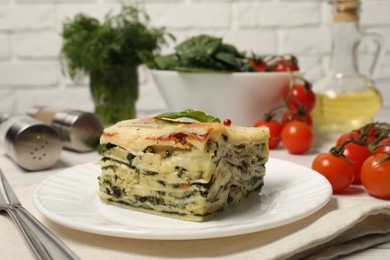 Photo of Piece of delicious spinach lasagne served on white table, closeup