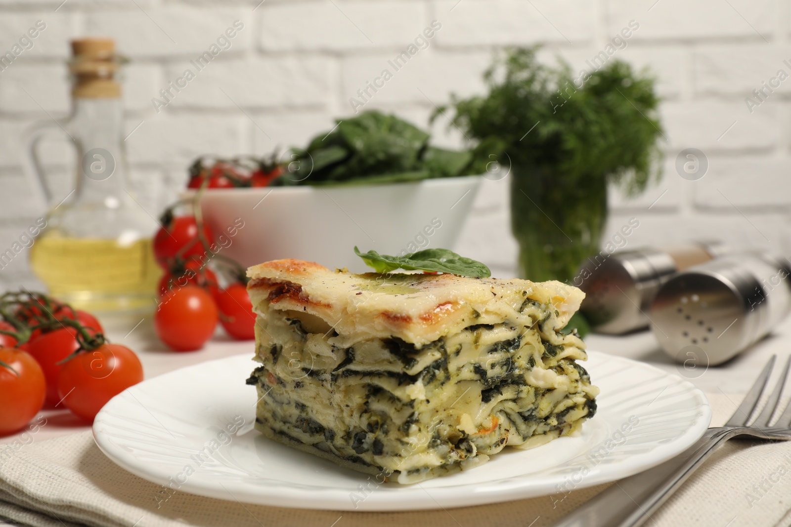 Photo of Piece of delicious spinach lasagne served on white table, closeup