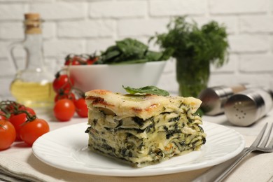 Photo of Piece of delicious spinach lasagne served on white table, closeup