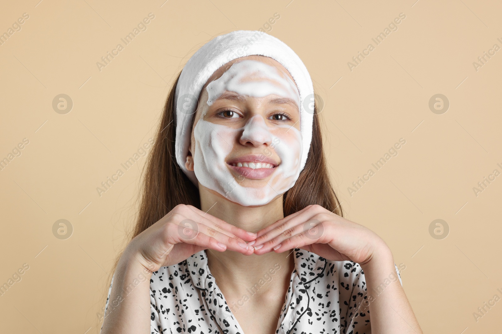 Photo of Teenage girl with cleansing foam on her face against beige background. Acne treatment