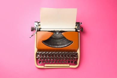Photo of Vintage typewriter with sheet of paper on pink background, top view