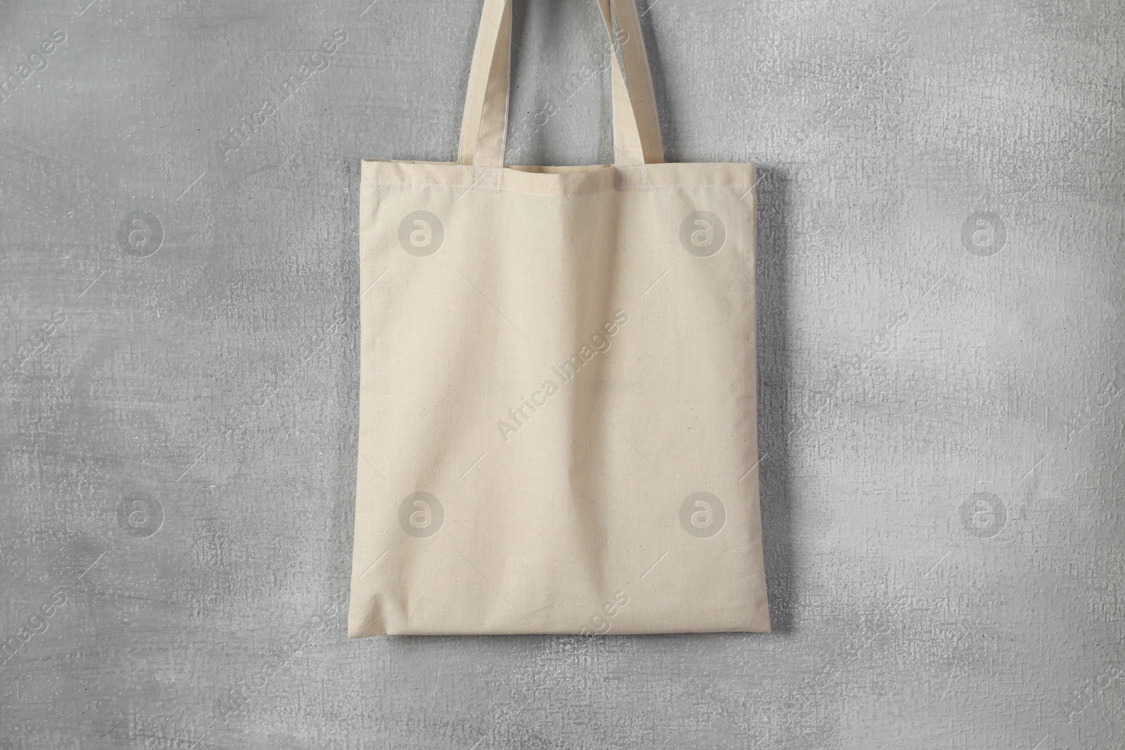 Photo of One eco bag hanging on grey wall. Mockup for design