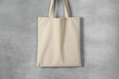 Photo of One eco bag hanging on grey wall. Mockup for design