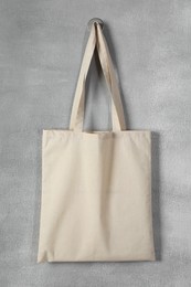 Photo of One eco bag hanging on grey wall. Mockup for design