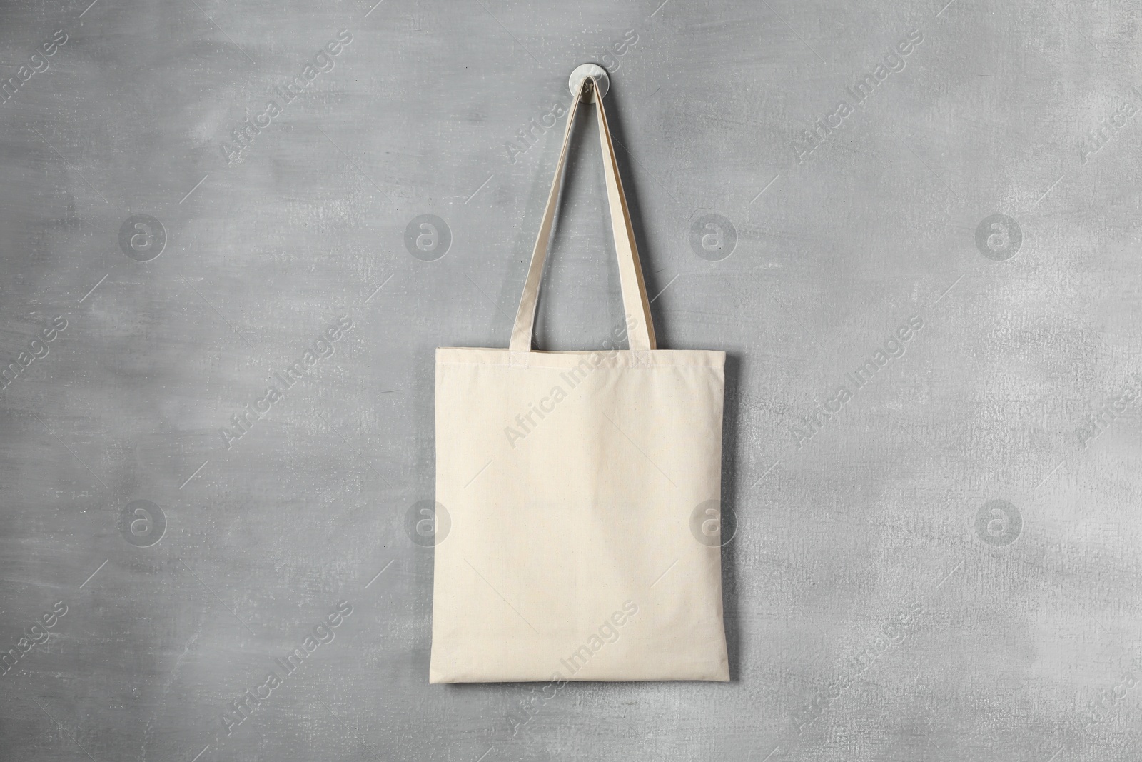 Photo of One eco bag hanging on grey wall. Mockup for design