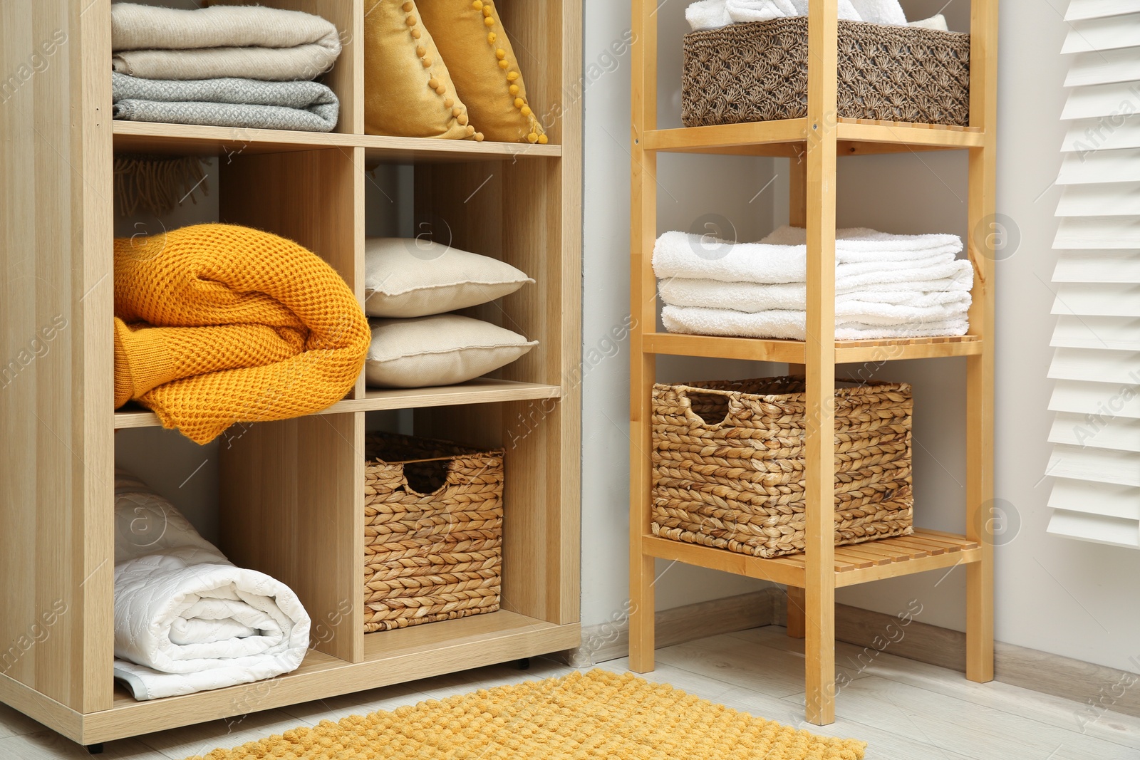 Photo of Home textile organization. Folded towels, blankets and pillows on shelving units indoors