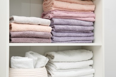 Photo of Home textile organization. Folded towels on shelving unit indoors, closeup