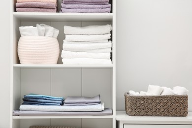 Photo of Home textile organization. Folded towels and bedsheets on shelving unit indoors