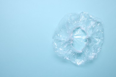 Photo of One shower cap on light blue background, top view. Space for text