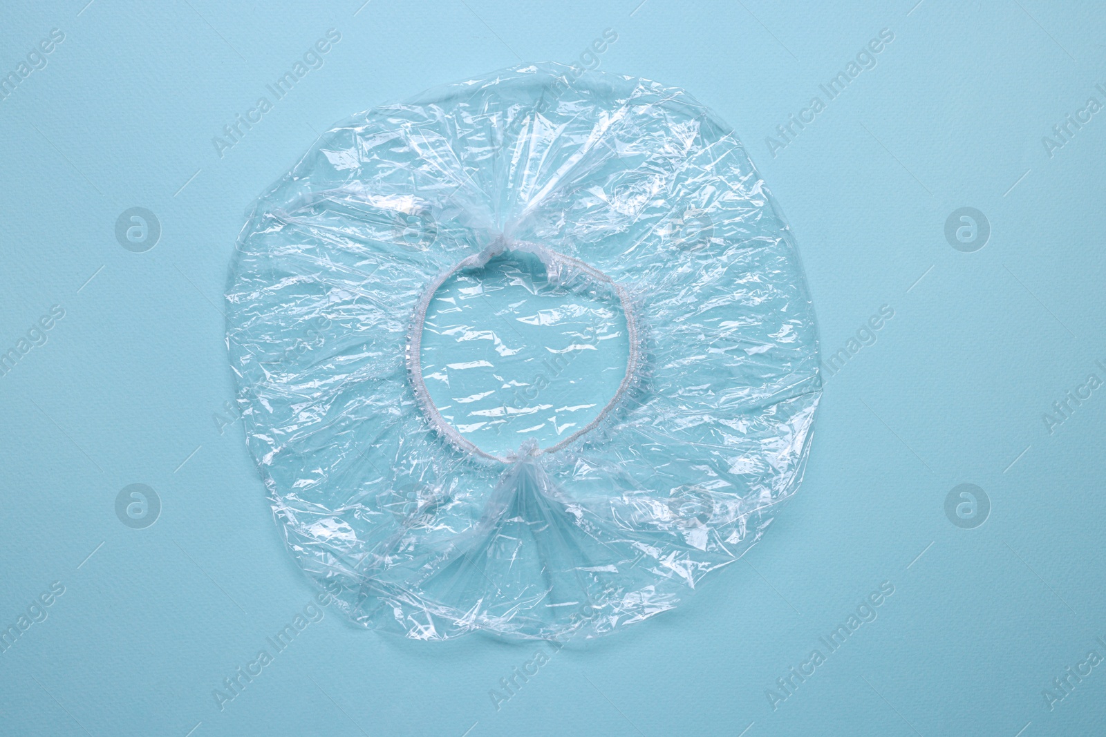 Photo of One shower cap on light blue background, top view