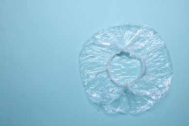 Photo of One shower cap on light blue background, top view. Space for text