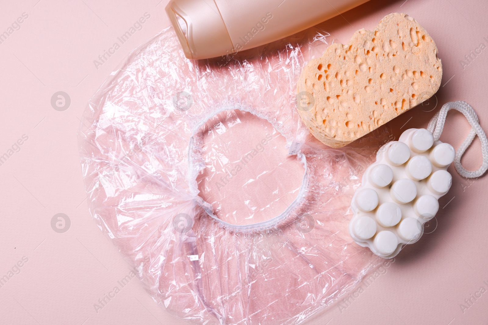 Photo of Shower cap and bath accessories on beige background, flat lay