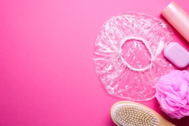 Photo of Shower cap and bath accessories on pink background, flat lay. Space for text