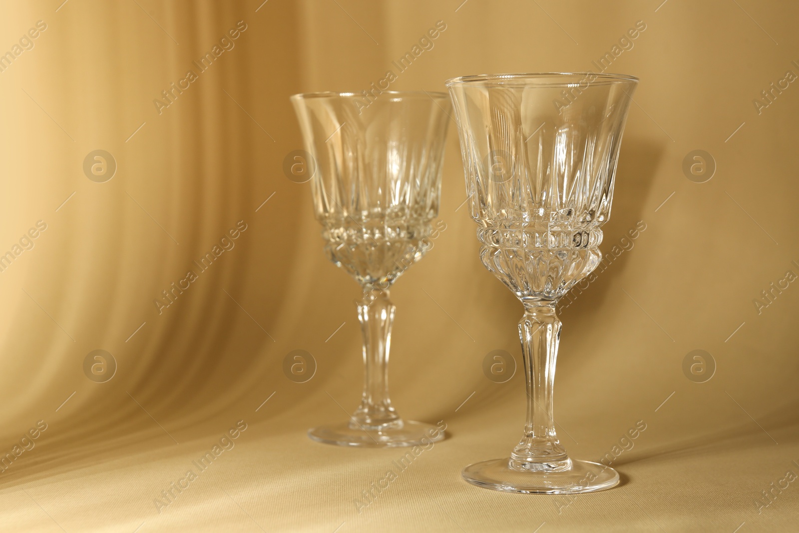 Photo of Two empty wine glasses on beige background, space for text