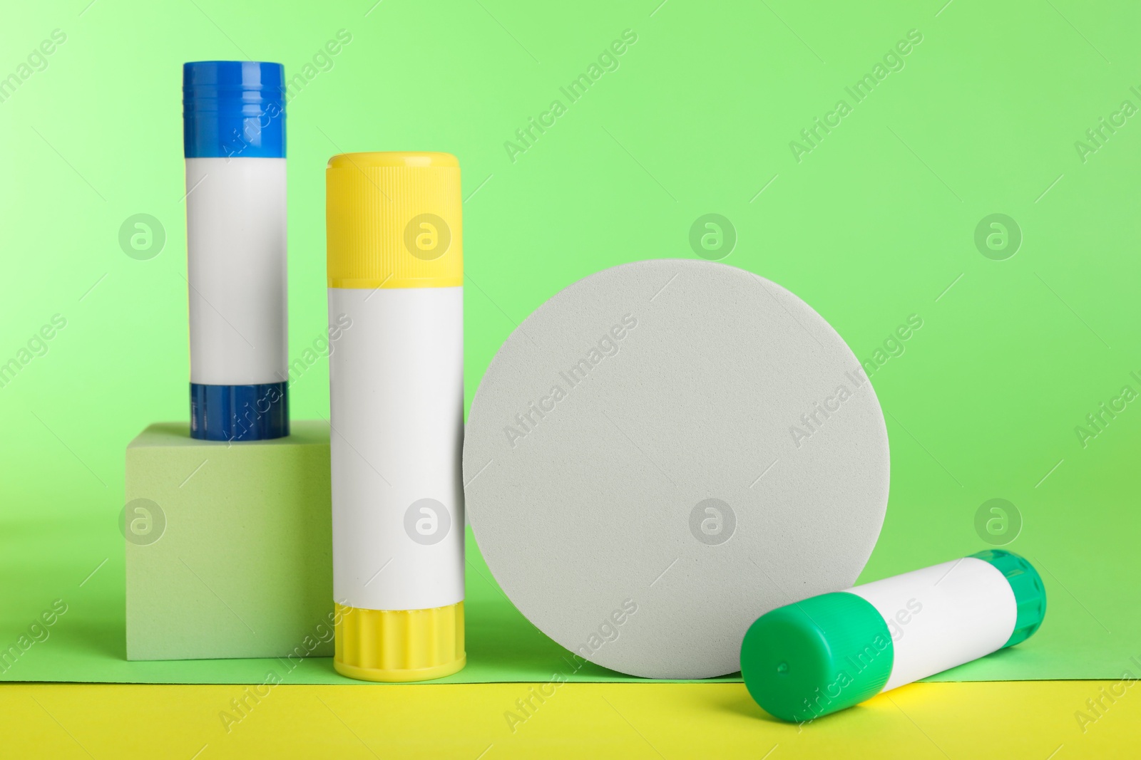 Photo of Glue sticks and podiums on light green background