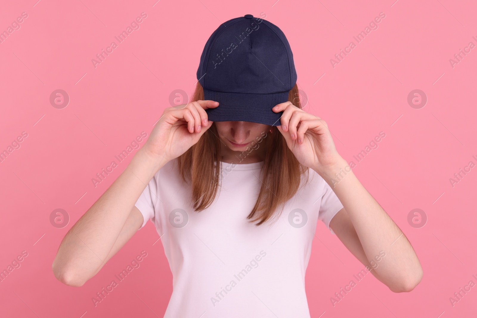 Photo of Woman in stylish baseball cap on pink background. Mockup for design