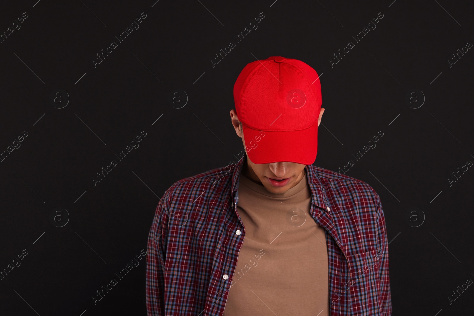 Photo of Man in stylish baseball cap on black background. Mockup for design