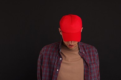 Photo of Man in stylish baseball cap on black background. Mockup for design