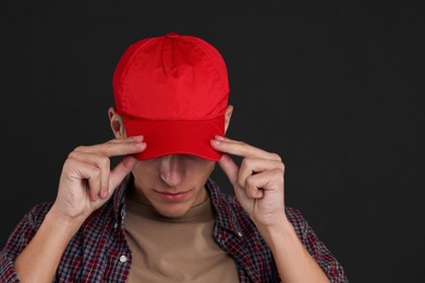 Photo of Man in stylish baseball cap on black background. Mockup for design