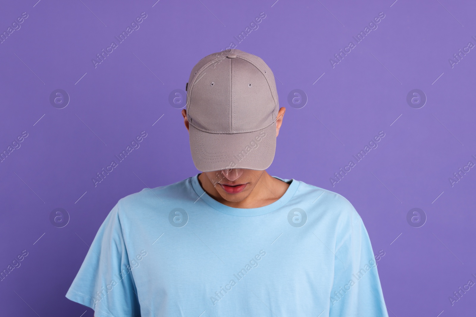 Photo of Man in stylish baseball cap on violet background. Mockup for design