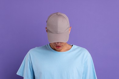 Photo of Man in stylish baseball cap on violet background. Mockup for design