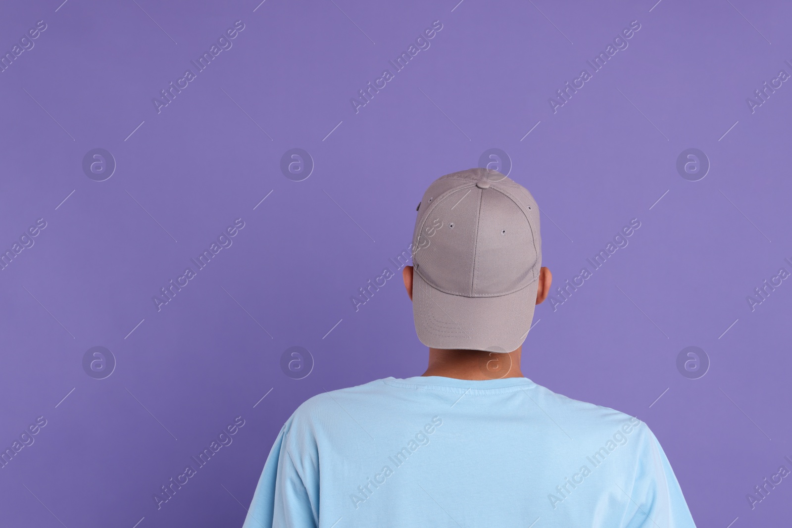 Photo of Man in stylish baseball cap on violet background, back view. Mockup for design