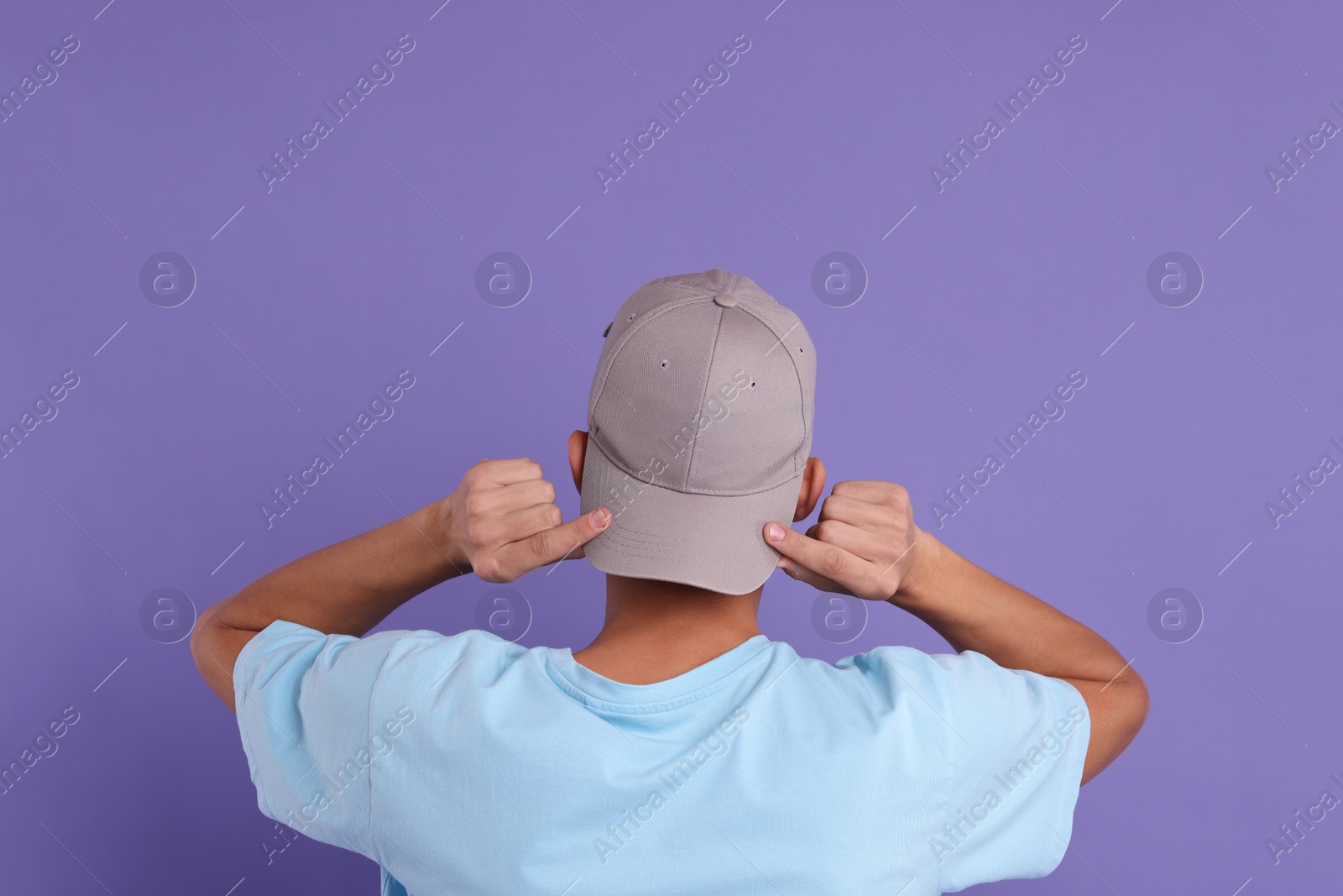 Photo of Man in stylish baseball cap on violet background, back view. Mockup for design