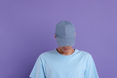 Photo of Man in stylish baseball cap on violet background. Mockup for design