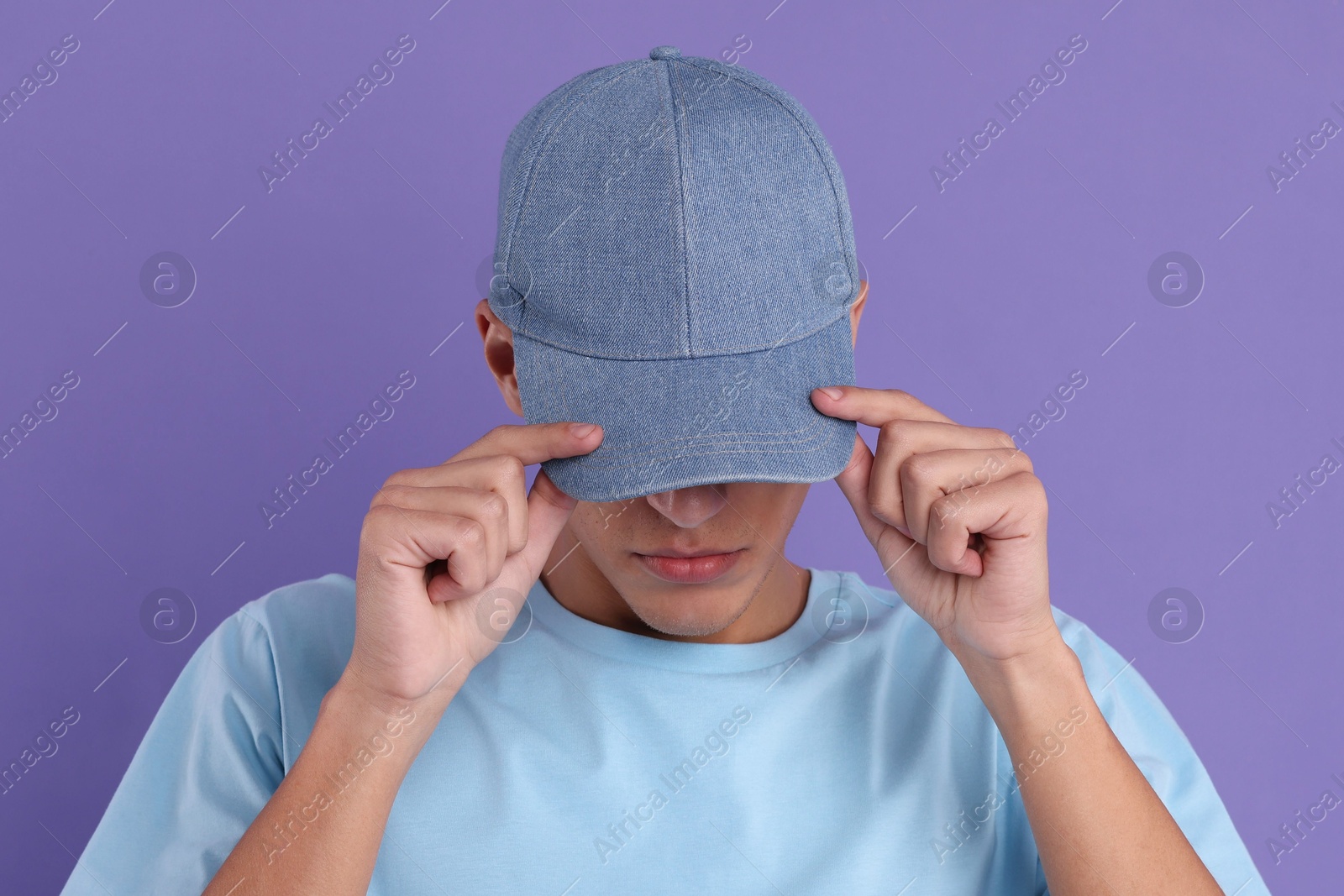 Photo of Man in stylish baseball cap on violet background. Mockup for design