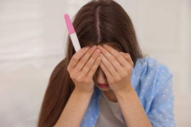 Photo of Upset woman with negative pregnancy test at home