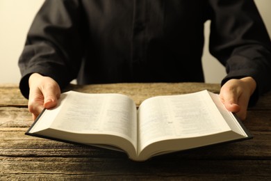 Photo of Woman with Holy Bible in English language at wooden table, closeup