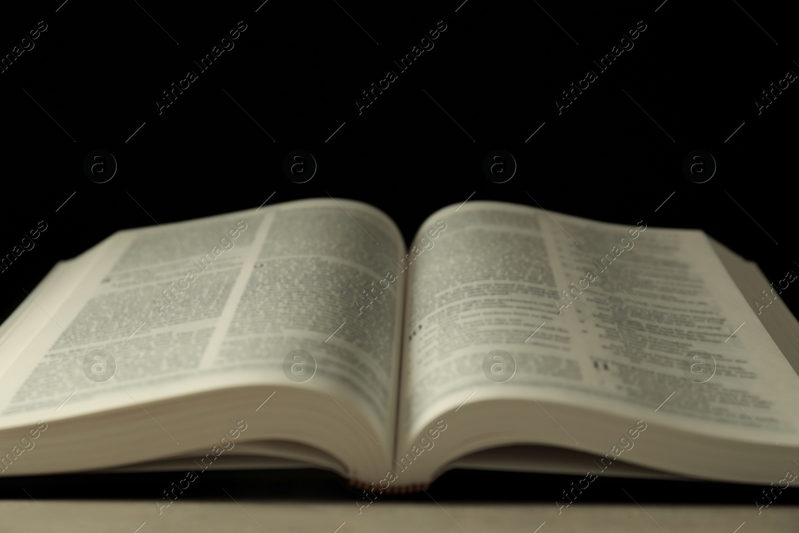 Photo of Open Holy Bible in English language on grey table, closeup