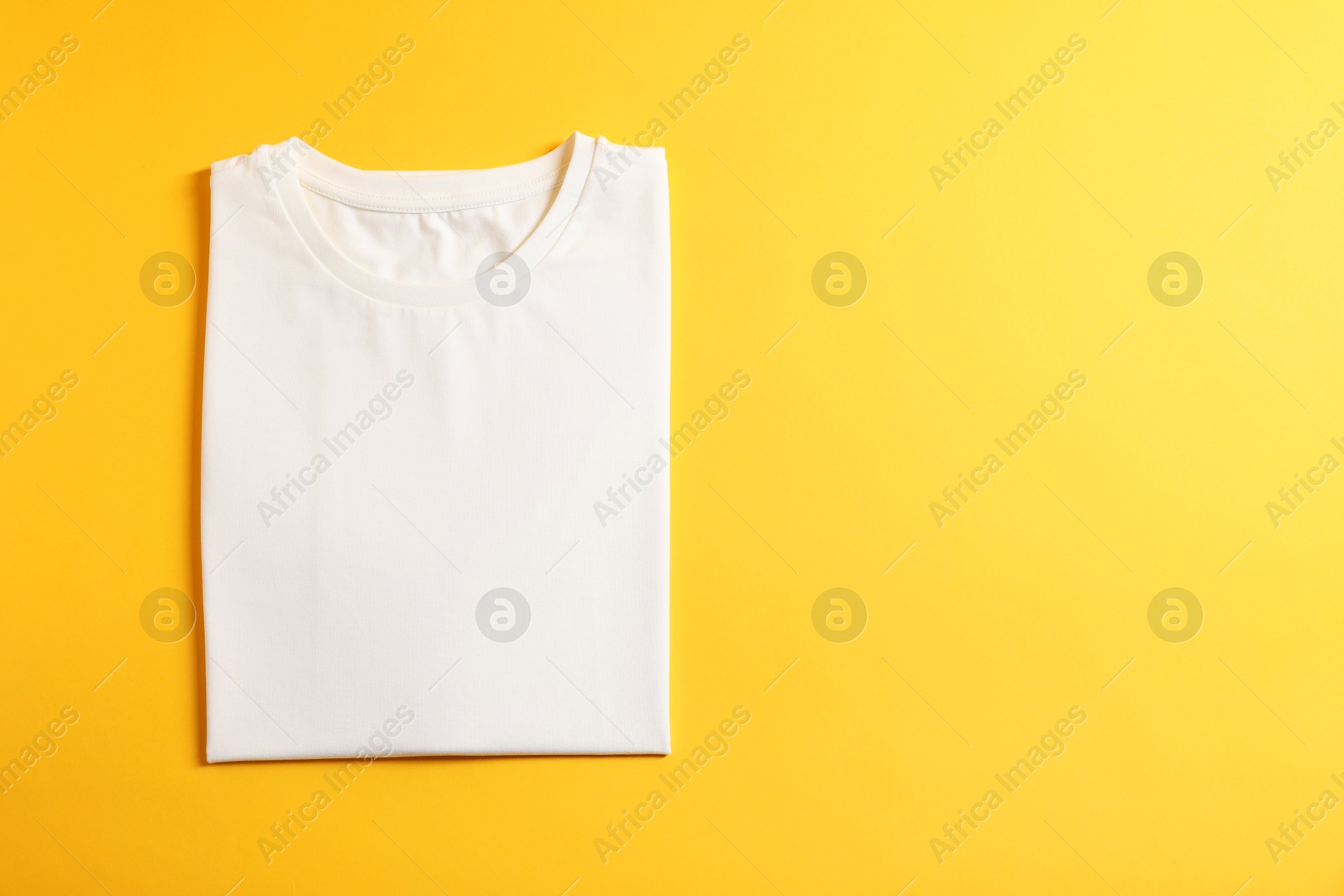 Photo of Blank white t-shirt on yellow background, top view. Mockup for design