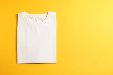 Photo of Blank white t-shirt on yellow background, top view. Mockup for design