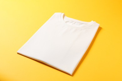 Photo of Blank white t-shirt on yellow background. Mockup for design