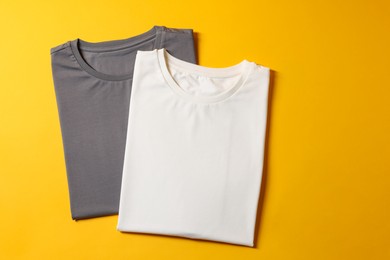 Photo of Different blank t-shirts on yellow background, top view. Mockup for design