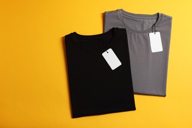 Photo of Different blank t-shirts on yellow background, top view. Mockup for design