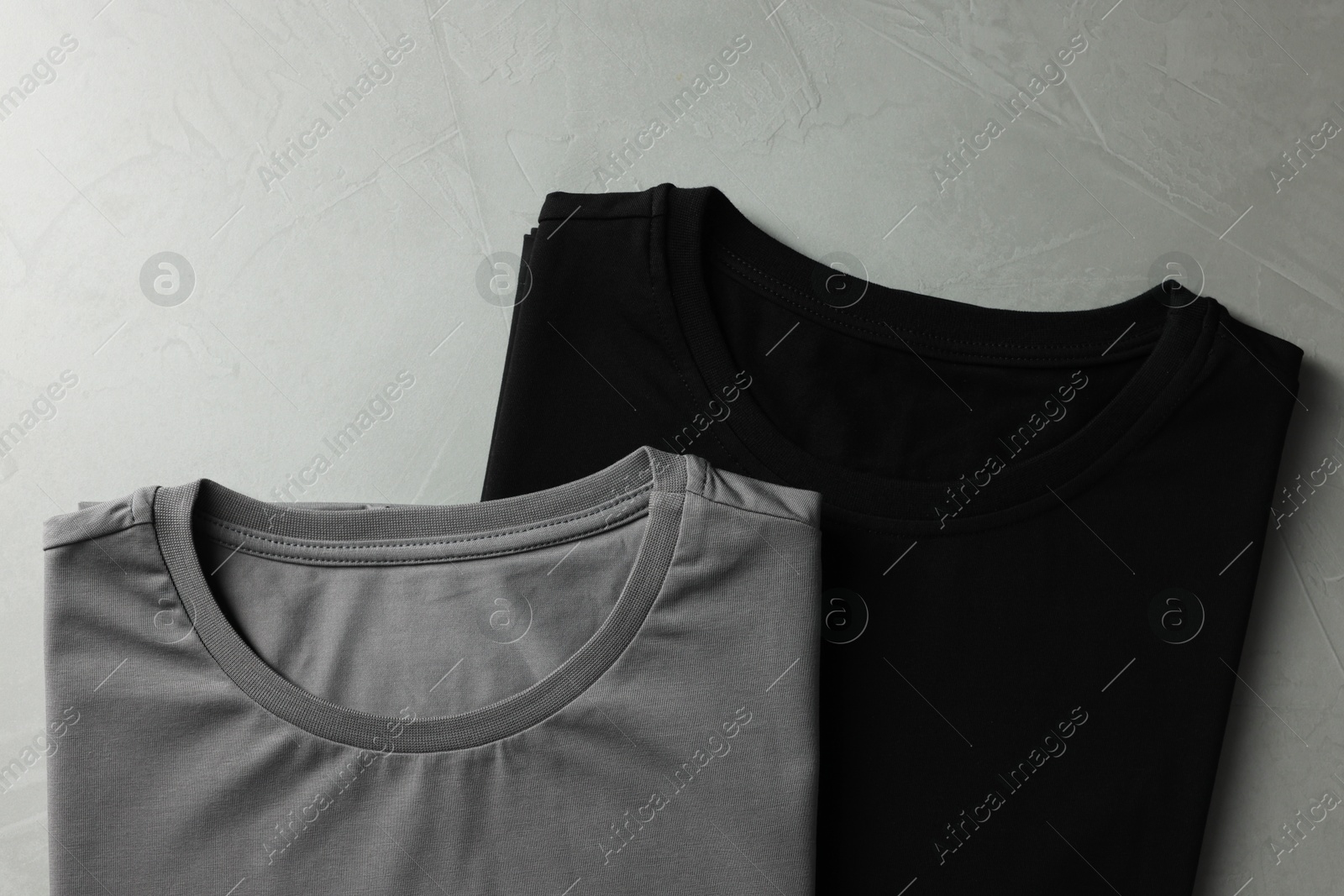 Photo of Different blank t-shirts on grey background, top view. Mockup for design