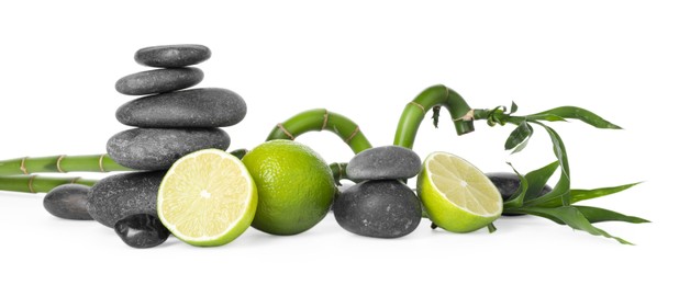 Photo of Spa composition with limes, massage stones and bamboo stems isolated on white