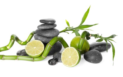 Photo of Spa composition with limes, massage stones and bamboo stems isolated on white