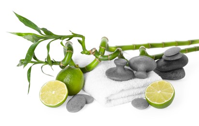 Photo of Spa composition with limes, massage stones, towel and bamboo stems isolated on white