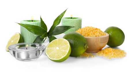 Photo of Spa composition with limes, burning candles, sea salt and green leaves on mirror surface against white background