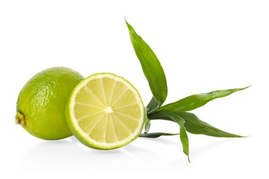 Photo of Fresh limes and bamboo leaves on mirror surface against white background