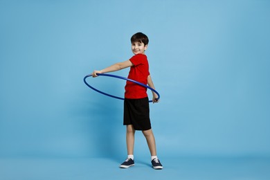 Photo of Boy exercising with hula hoop on light blue background