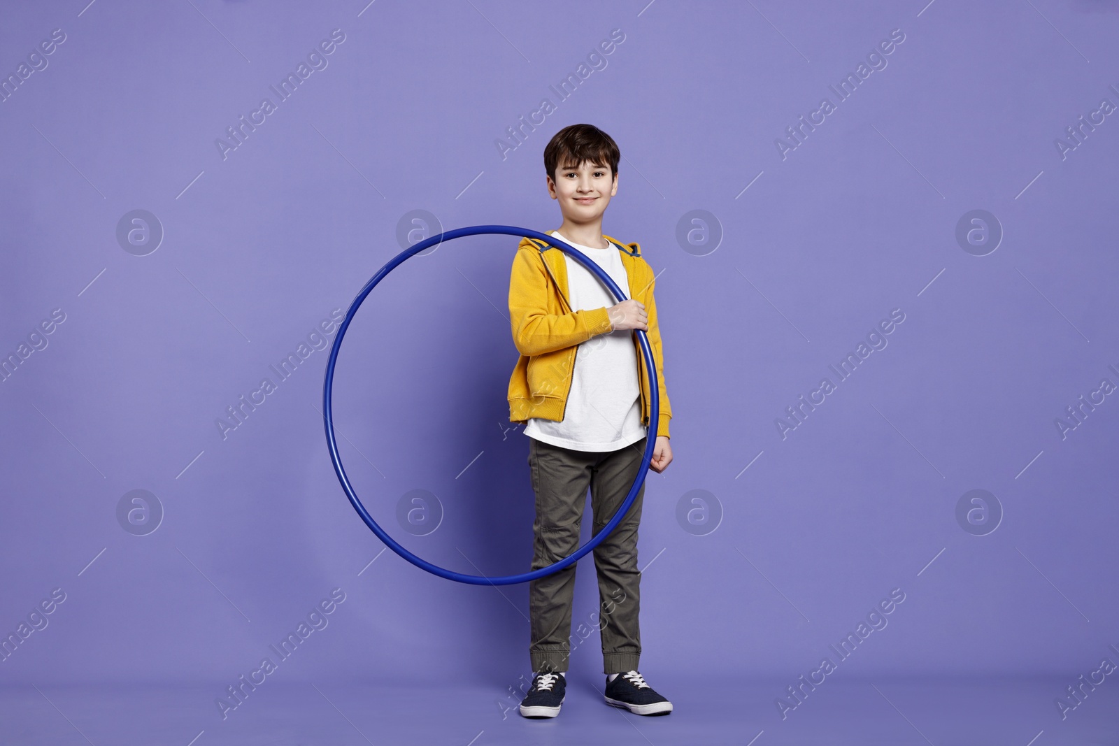 Photo of Smiling boy with hula hoop on violet background