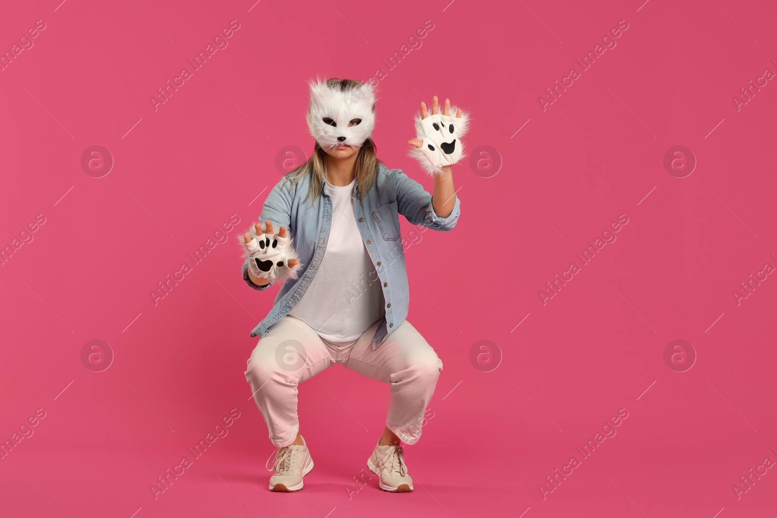 Photo of Quadrobics. Woman wearing cat mask and gloves on pink background