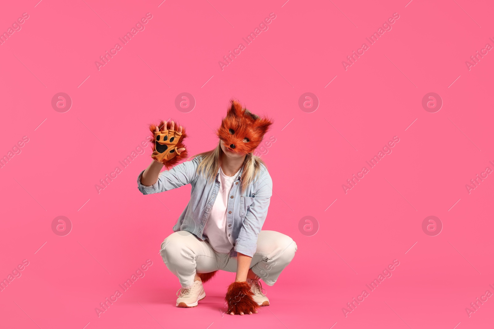 Photo of Quadrobics. Woman wearing fox mask and gloves pink background